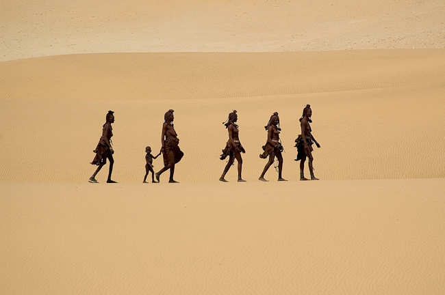 Himba people walking on the dunes at Serra Cafema in Namibia